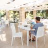 Uomo seduto su una terrazza legge una rivista.
