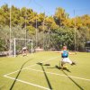 Bambino tira un calcio a un pallone verso una porta su un campo sportivo all'aperto.
