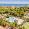 Vista aerea di un villaggio turistico con piscina vicino al mare.