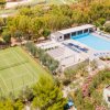 Campo da tennis e piscina in un'area verde.