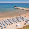 Spiaggia con ombrelloni blu e mare calmo.