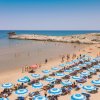 Spiaggia affollata con ombrelloni azzurri.