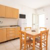 Cucina chiara con tavolo e sedie in legno.