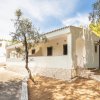 Casa bianca circondata da alberi e ombra.