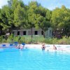 Piscina all'aperto con bagnanti e alberi sullo sfondo.