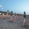 Spiaggia all'alba con lettini e ombrelloni colorati.