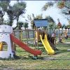 Parco giochi con scivoli colorati e alberi sullo sfondo.