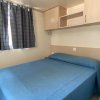 Letto matrimoniale con copriletto blu e armadietti pensili.