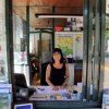 Donna sorridente seduta al banco accoglienza con vetrata per il check-in.