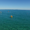 Persone su kayak gialli e arancioni remano sul mare cristallino con cielo sereno.