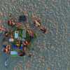 Gruppo di persone vista dall'alto su una spiaggia, attorno a un picnic.