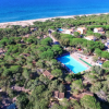 Complesso residenziale con piscina tra gli alberi, vicino a una spiaggia e il mare.