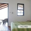Stanza da letto con finestra e porta aperta verso un patio con sedie.