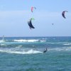 Kitesurfer in mare con vele colorate e onde.