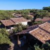 Complesso di edifici con tetti in tegole circondato da vegetazione.