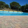 Una piscina all'aperto con sedie a sdraio, circondata da alberi e un cielo blu.