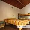 Camera con letto matrimoniale e letti a castello, coperte a righe giallo-arancio.