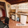 Cucina esterna con lavello, fornello, e frigorifero su pavimento piastrellato.