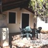 Un villino con veranda, tavolo e sedie all'aperto. Alberi circostanti.